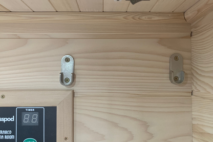 Wooden sauna door with digital timer and control panel on a wooden wall.