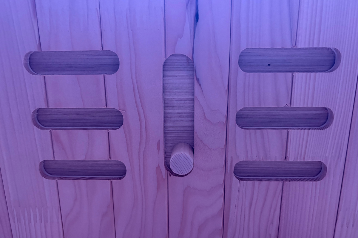 Wooden door with a doorknob and five rectangular handles on a wooden wall.