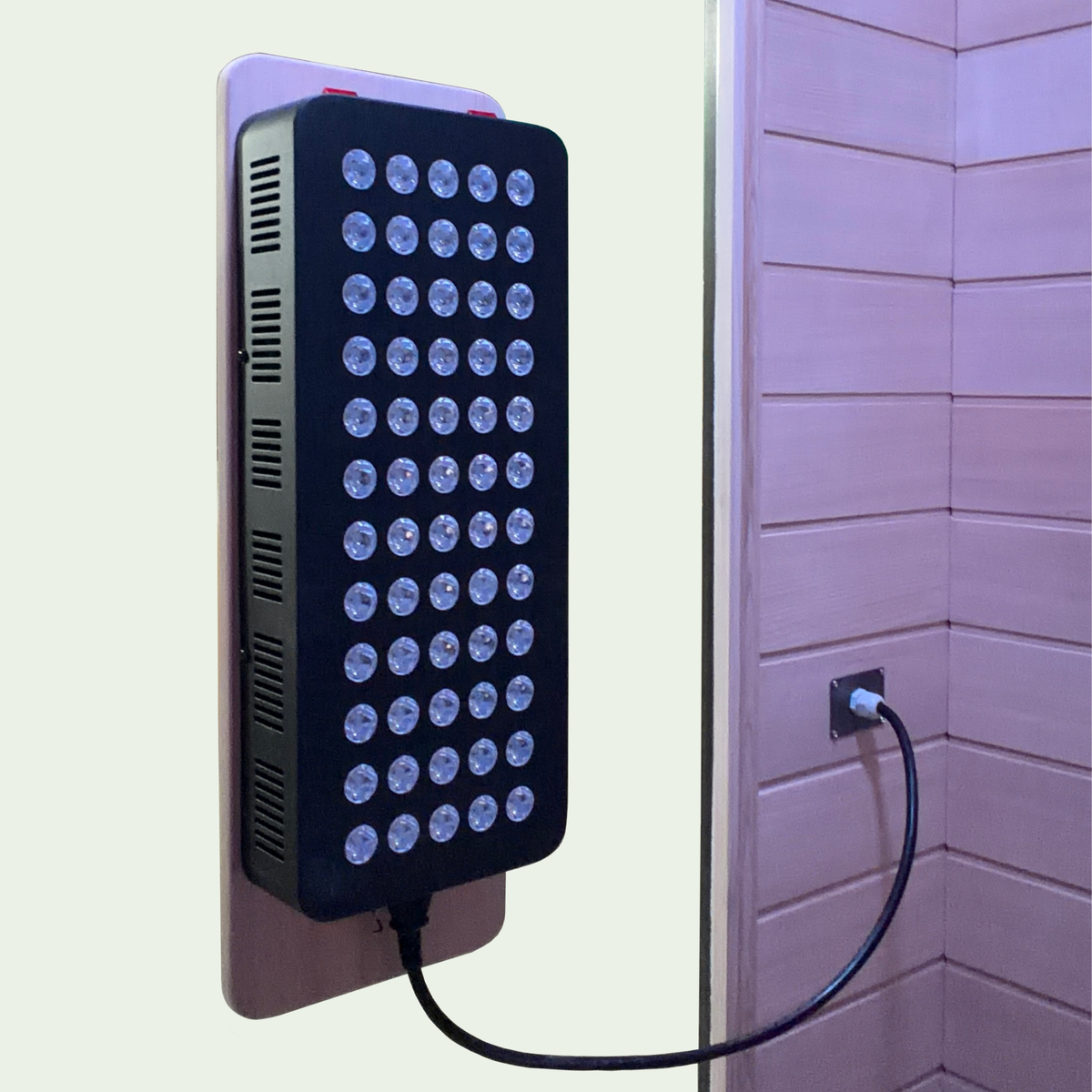 LED light panel attached to a wall with a power cord plugged into an outlet.