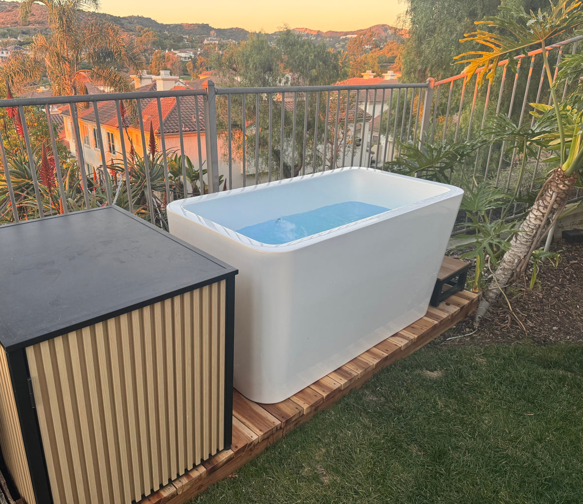 White outdoor bathtub on a wooden platform with a scenic background