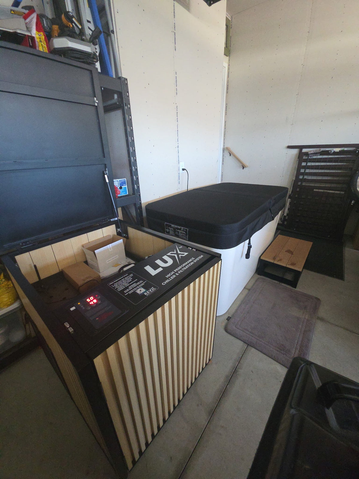 A luxury outdoor hot tub and matching wood-paneled control console in a garage setting.