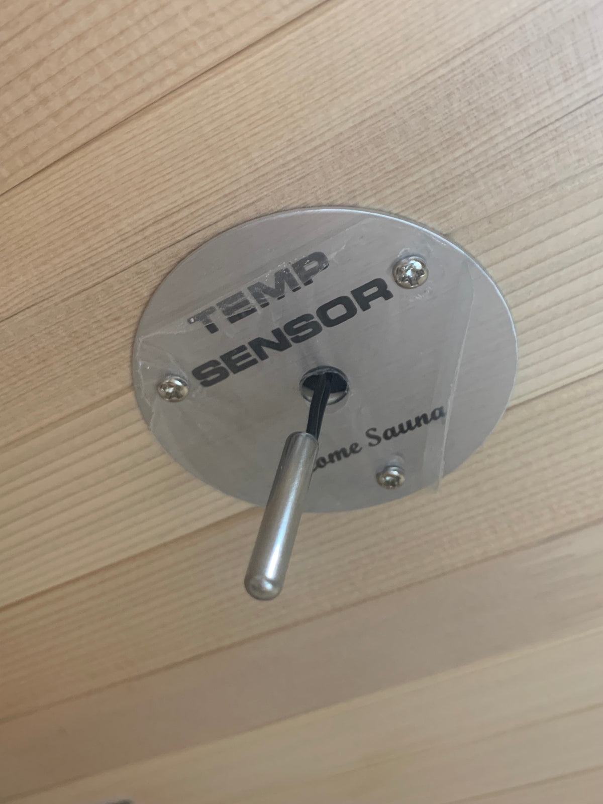 Metallic temperature sensor on a wooden surface